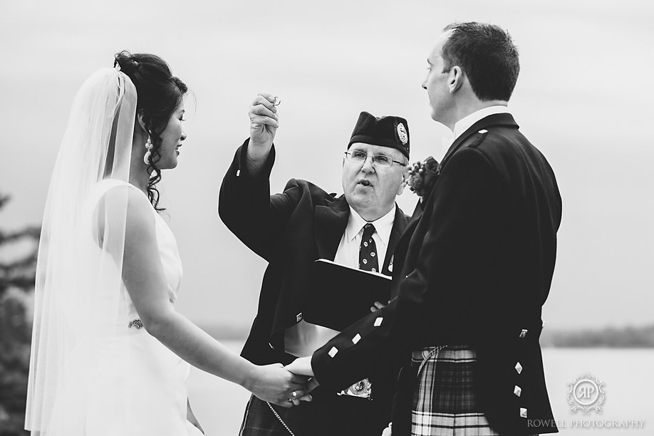 officient presenting the ring to the couple on the windermere house lawn during the ceremony